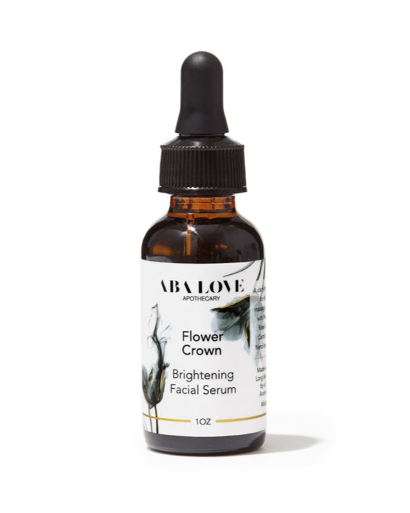 Amber glass bottle with black dropper. White label with black and grey graphic and black type that reads Flower Crown Brightening Facial Serum, 1 oz bottle. There is a thin gold label printed around the bottom of the label