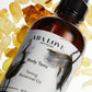 Amber colored bottle with black treatment pump.  "Aba Love Apothecary Body Tonic Toning Botanical Oil". The label is white with gold trim and grey flowers. The bottle lays flat on pieces of yellow colored frankincense resin